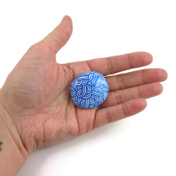 Magnet réalisé avec un faux galet rond peint blanc aux volutes bleues métallisées