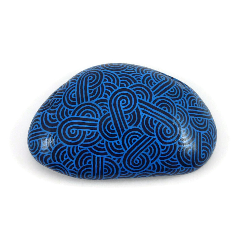 Painted pebble with sky blue zentangle on navy blue background