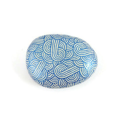 Painted pebble with metallic royal blue doodles on white background