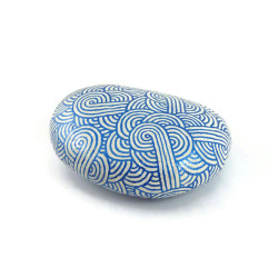 Painted pebble with metallic royal blue doodles on white background