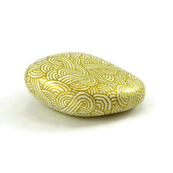 Painted pebble with golden doodles on white background