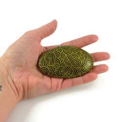 Painted pebble with golden doodles on black background
