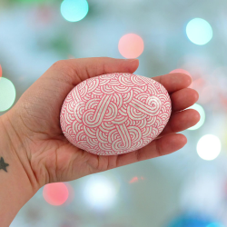 Painted pebble with candy pink doodles on white background