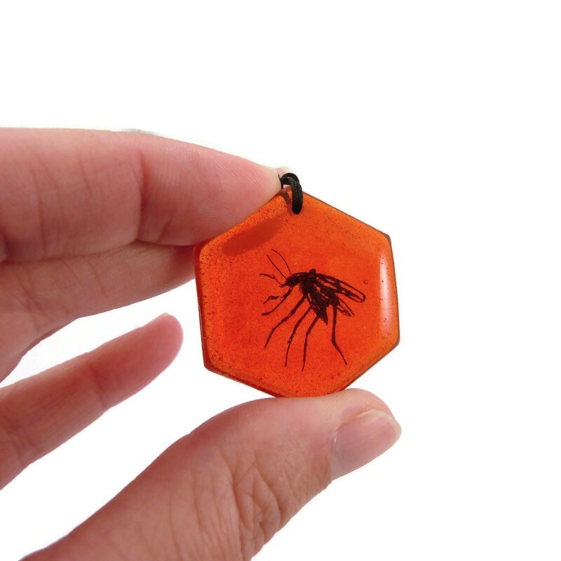 Hexagonal charm representing a mosquito trapped in amber