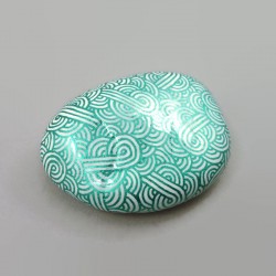 Painted pebble with metallic green doodles on white background