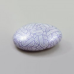 Painted pebble with metallic purple doodles on white background