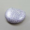 Painted pebble with metallic purple doodles on white background