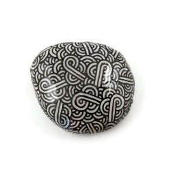 Phosphorescent white painted pebble with black doodles