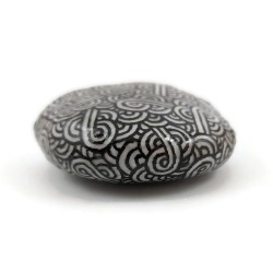 Phosphorescent white painted pebble with black doodles
