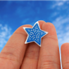 Eco-friendly pin badge in the form of white star with metallic blue doodles