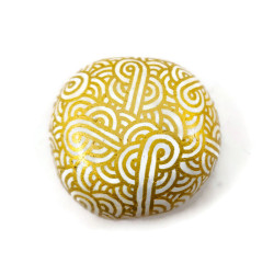 Small painted pebble with golden doodles on white background