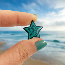 Dark green star pin badge with emerald doodles