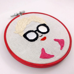 Broderie d'un visage de femme à lunettes