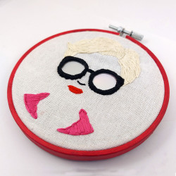 Broderie d'un visage de femme à lunettes