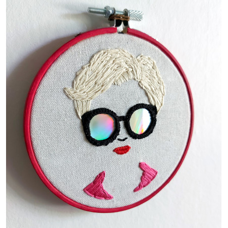 Broderie d'un visage de femme à lunettes