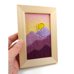 Embroidery of a sunset over mountains