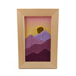 Embroidery of a sunset over mountains