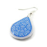 Boucle d'oreille goutte blanche aux volutes bleues métallisées (Vendue à l'unité)
