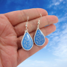 Boucles d'oreilles pendantes en forme de petites gouttes blanches aux volutes bleues métallisées (Vendues à l'unité)